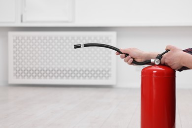 Photo of Man with fire extinguisher indoors, closeup. Space for text