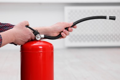 Photo of Man with one fire extinguisher indoors, closeup