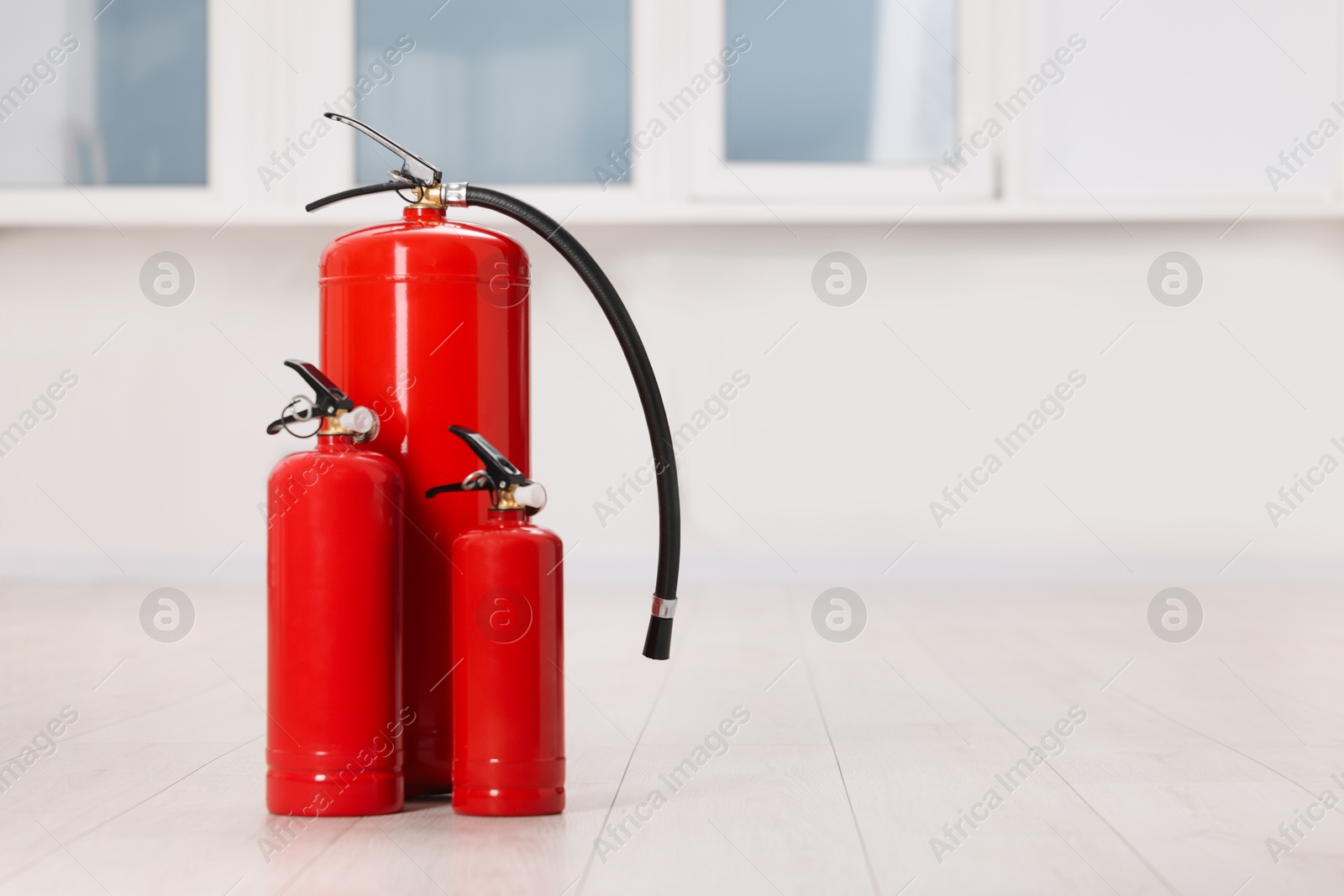 Photo of Fire extinguishers on floor indoors, space for text