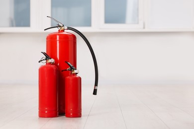 Photo of Fire extinguishers on floor indoors, space for text