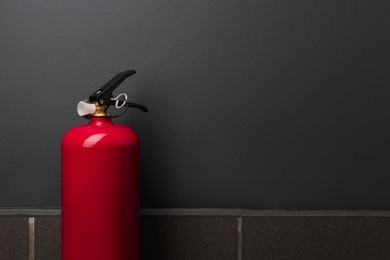 Photo of One fire extinguisher near grey wall, space for text