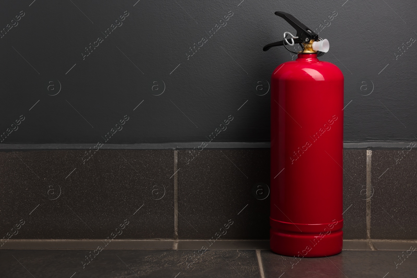 Photo of One fire extinguisher on floor near grey wall, space for text