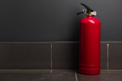 Photo of One fire extinguisher on floor near grey wall, space for text