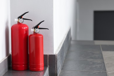 Photo of Fire extinguishers on floor in hall, space for text