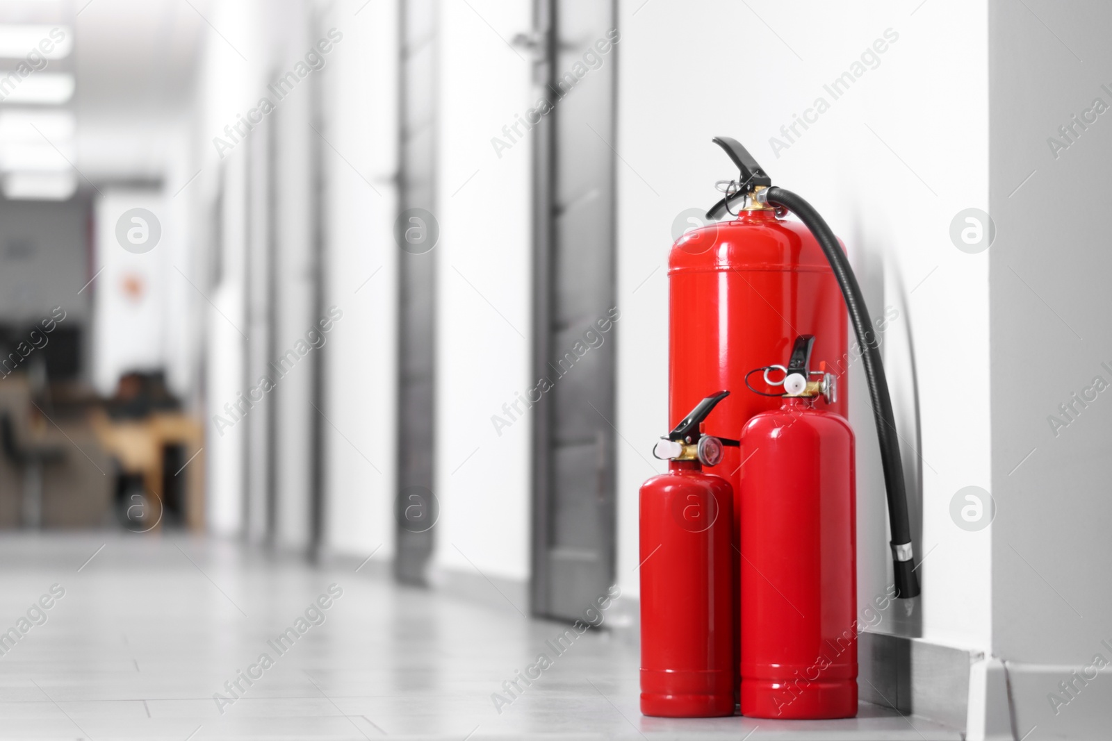 Photo of Fire extinguishers on floor in hall, space for text