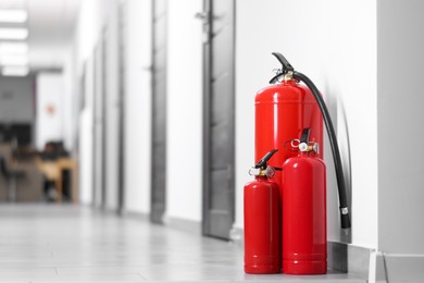 Photo of Fire extinguishers on floor in hall, space for text