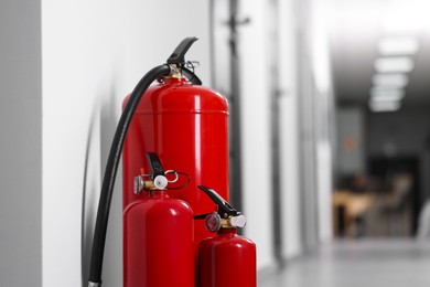 Photo of Fire extinguishers in hall, closeup. Space for text