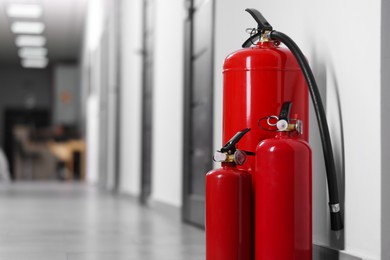 Photo of Fire extinguishers in hall, closeup. Space for text