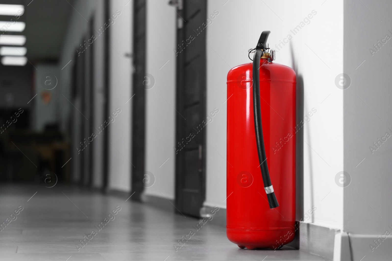 Photo of Fire extinguisher on floor in hall, space for text