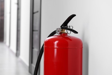 Photo of One red fire extinguisher in hall, closeup