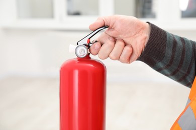 Photo of Man with one fire extinguisher indoors, closeup