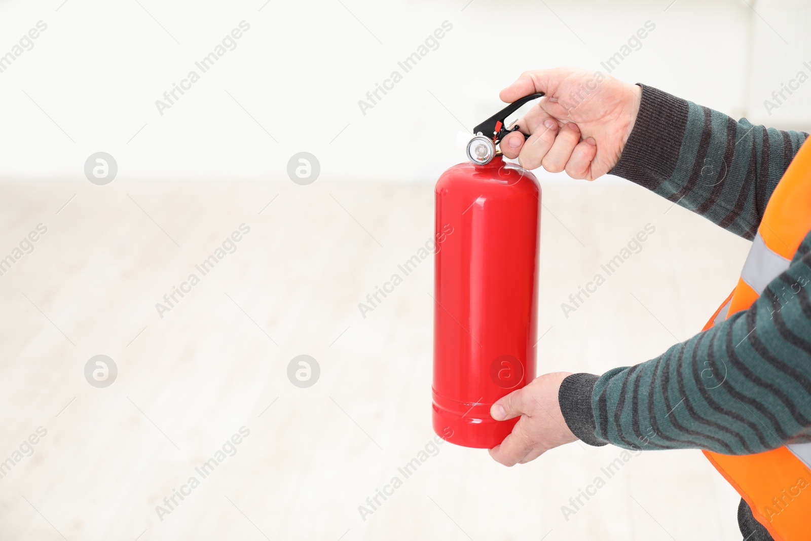 Photo of Man with fire extinguisher indoors, closeup. Space for text