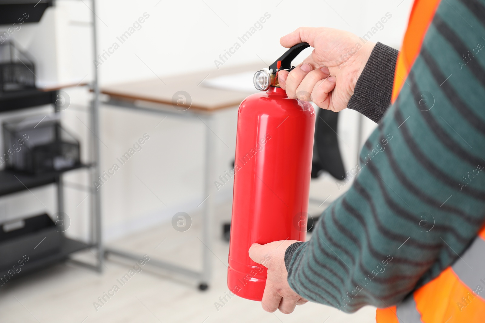 Photo of Man with fire extinguisher indoors, closeup. Space for text