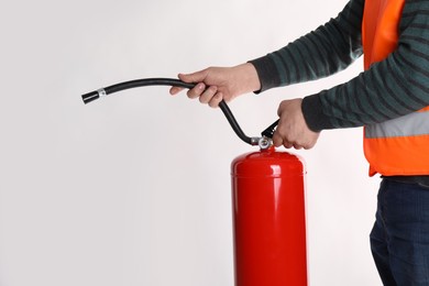 Photo of Man with fire extinguisher on light background, closeup