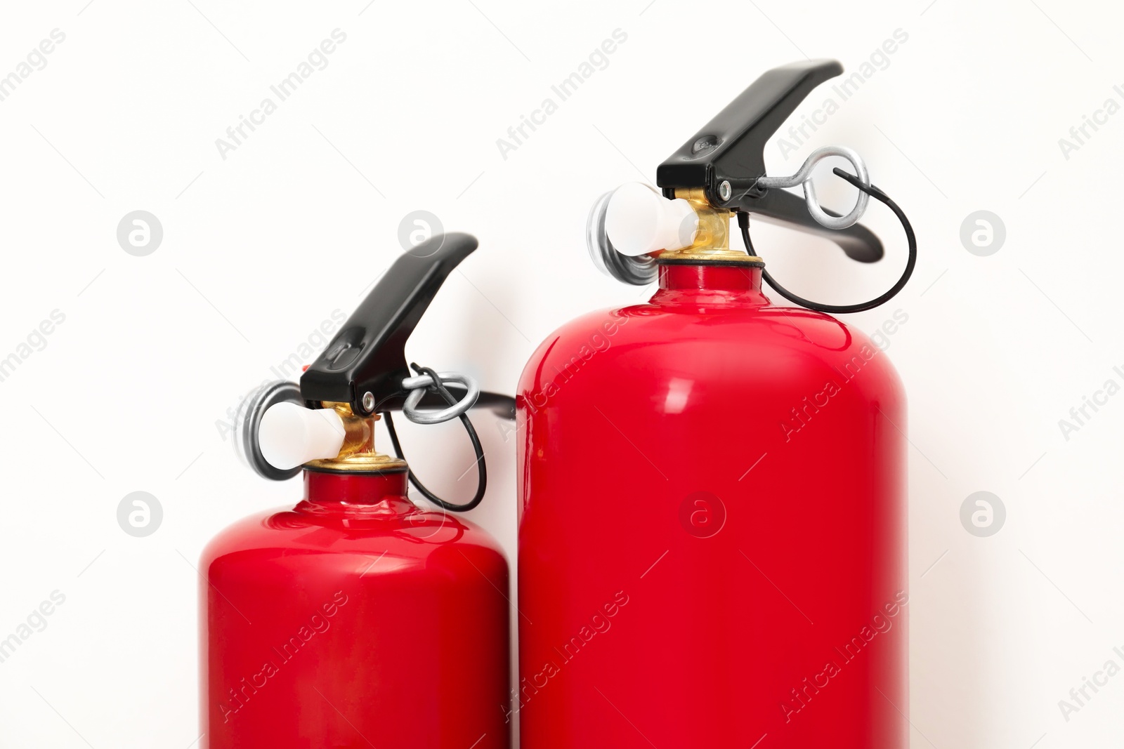 Photo of Two fire extinguishers on light background, closeup