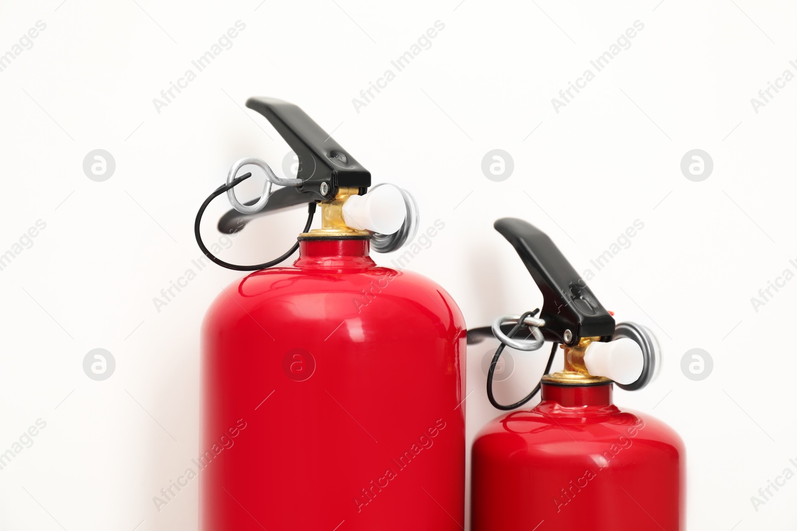 Photo of Two fire extinguishers on light background, closeup