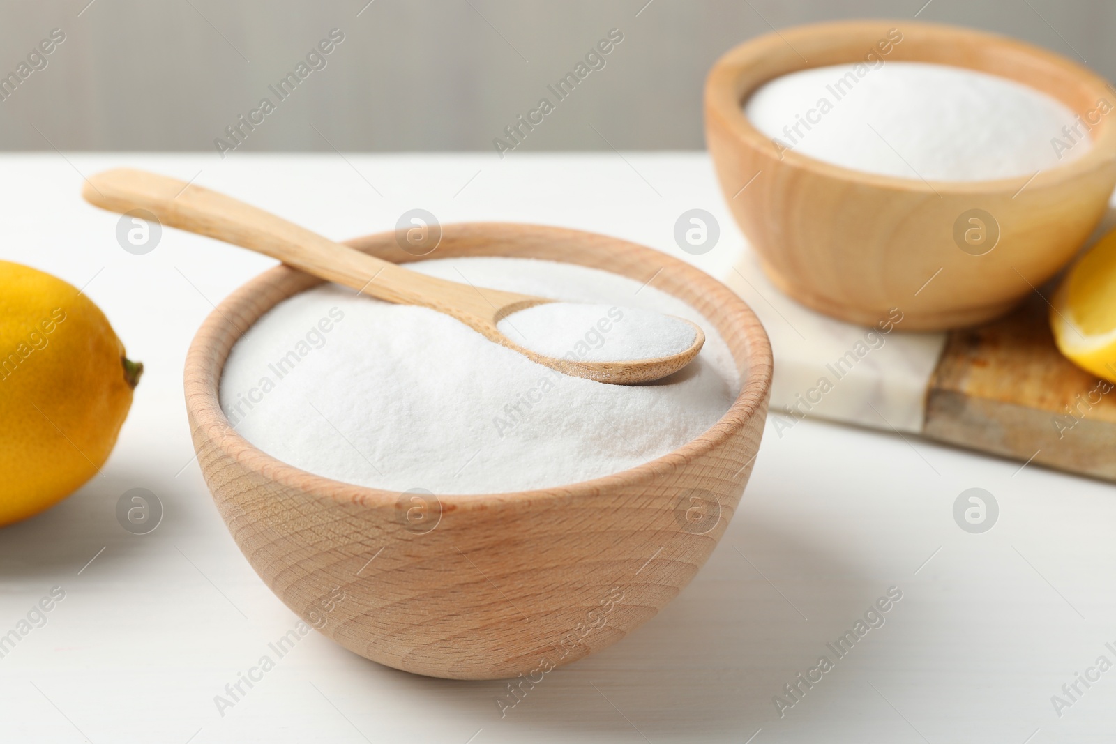 Photo of Baking soda and lemons on white wooden table, closeup