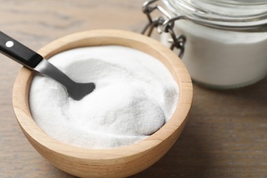 Photo of Baking soda in bowl on wooden table, closeup