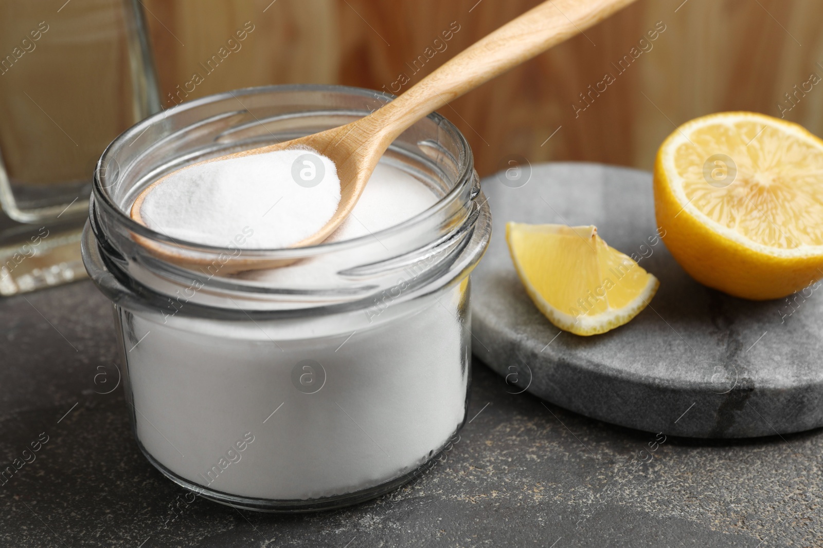 Photo of Baking soda and lemon on grey table, closeup