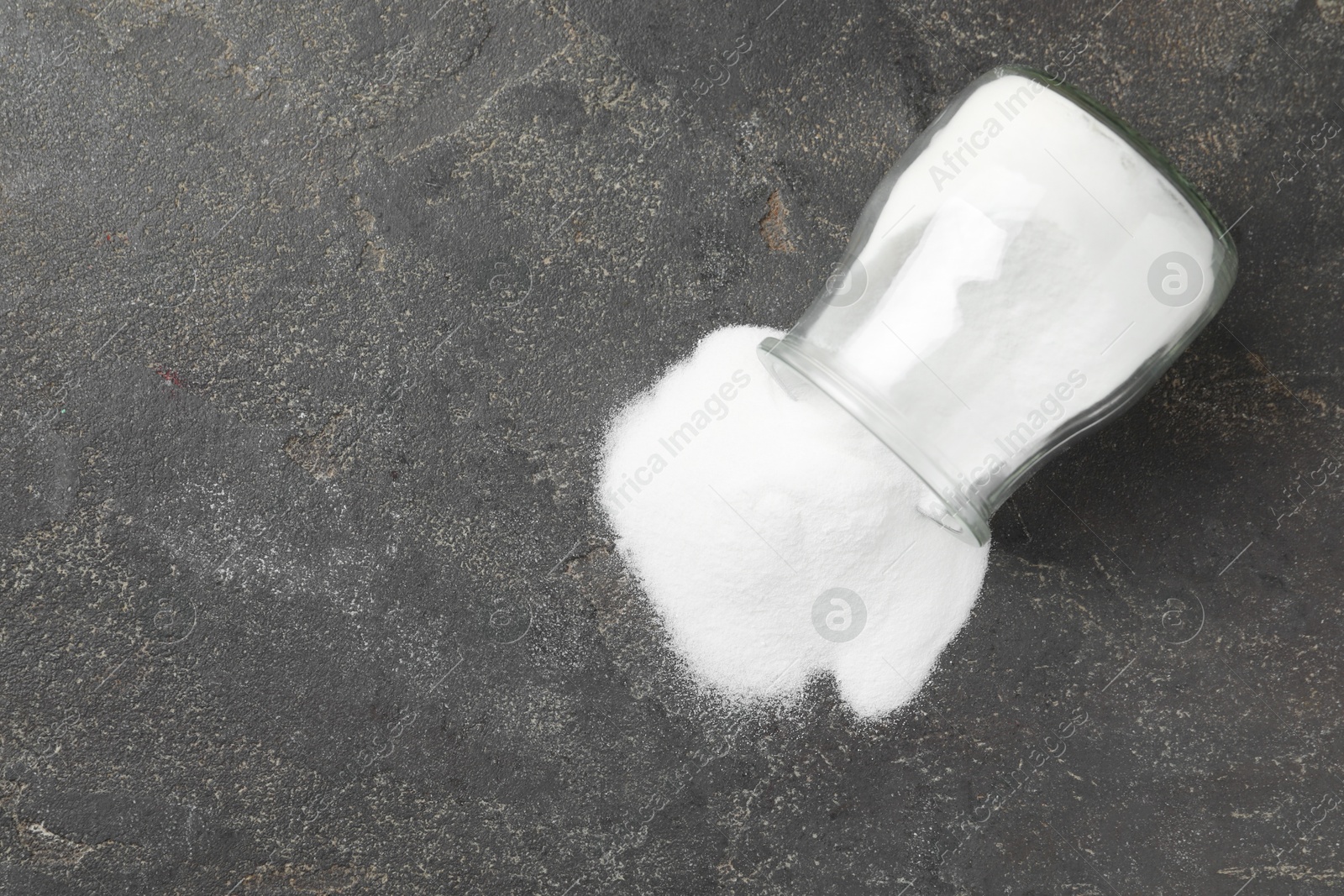 Photo of Baking soda in glass jar on grey table, top view. Space for text