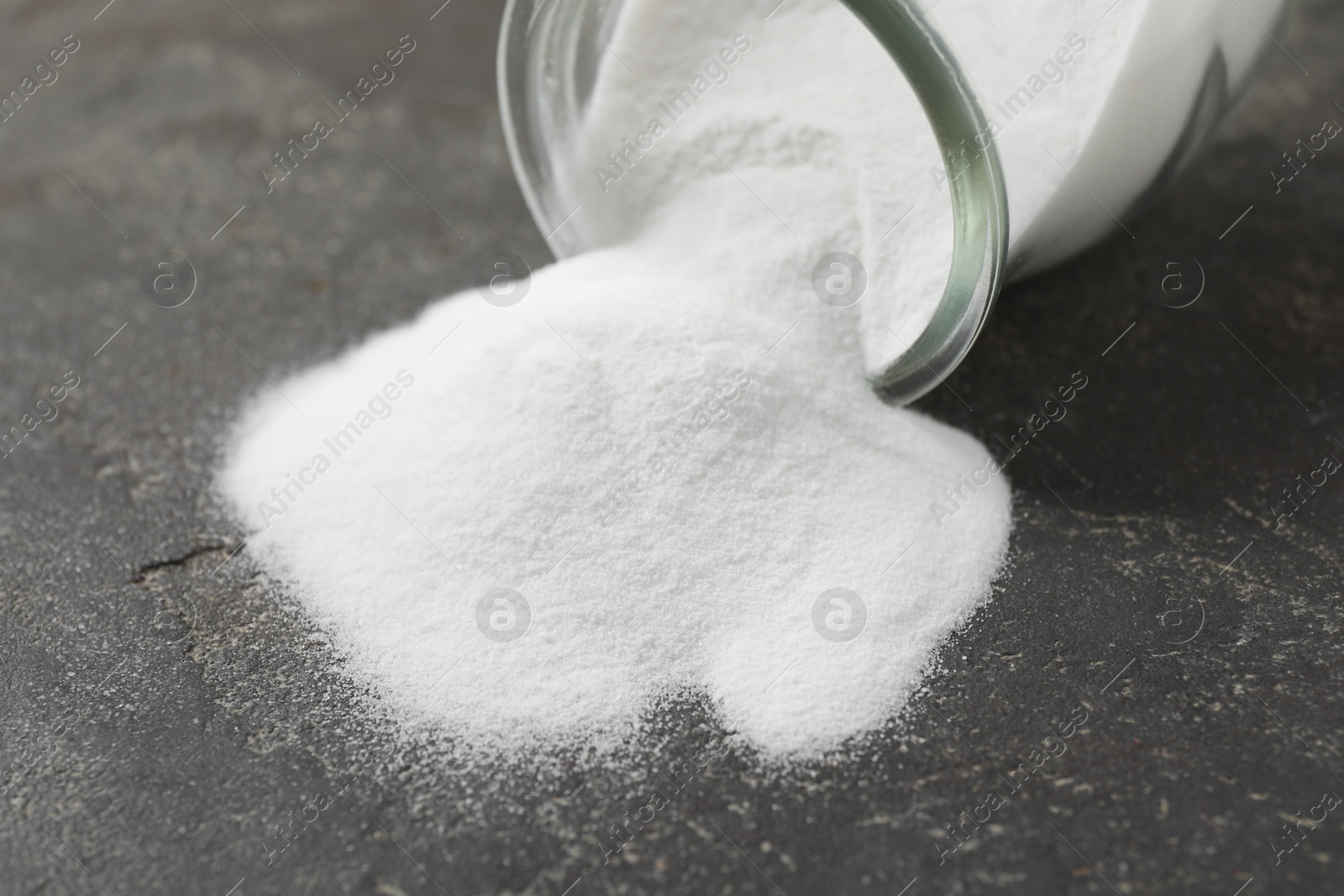 Photo of Baking soda in glass jar on grey table, closeup