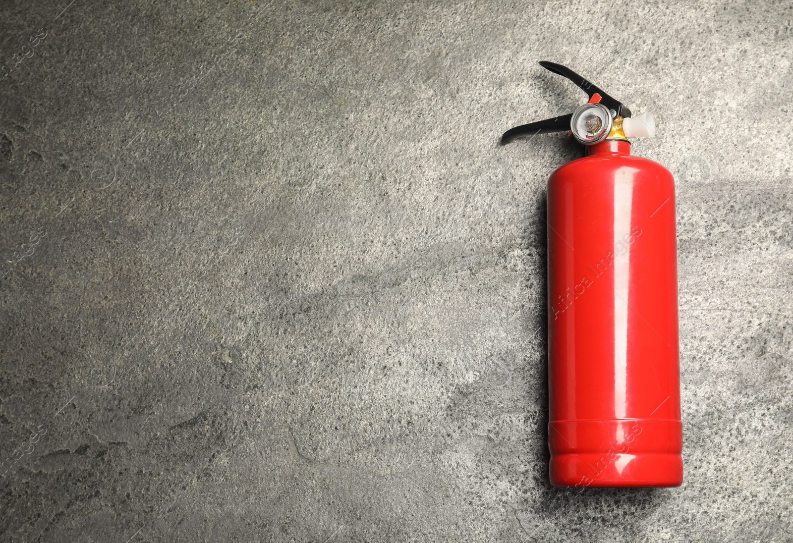 Photo of One red fire extinguisher on gray textured background, top view. Space for text