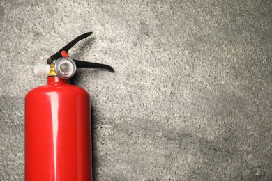 Photo of One red fire extinguisher on gray textured background, top view. Space for text