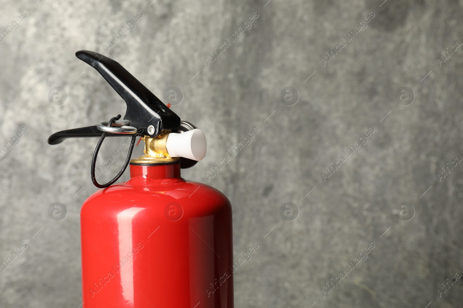 Photo of One red fire extinguisher on gray background, space for text