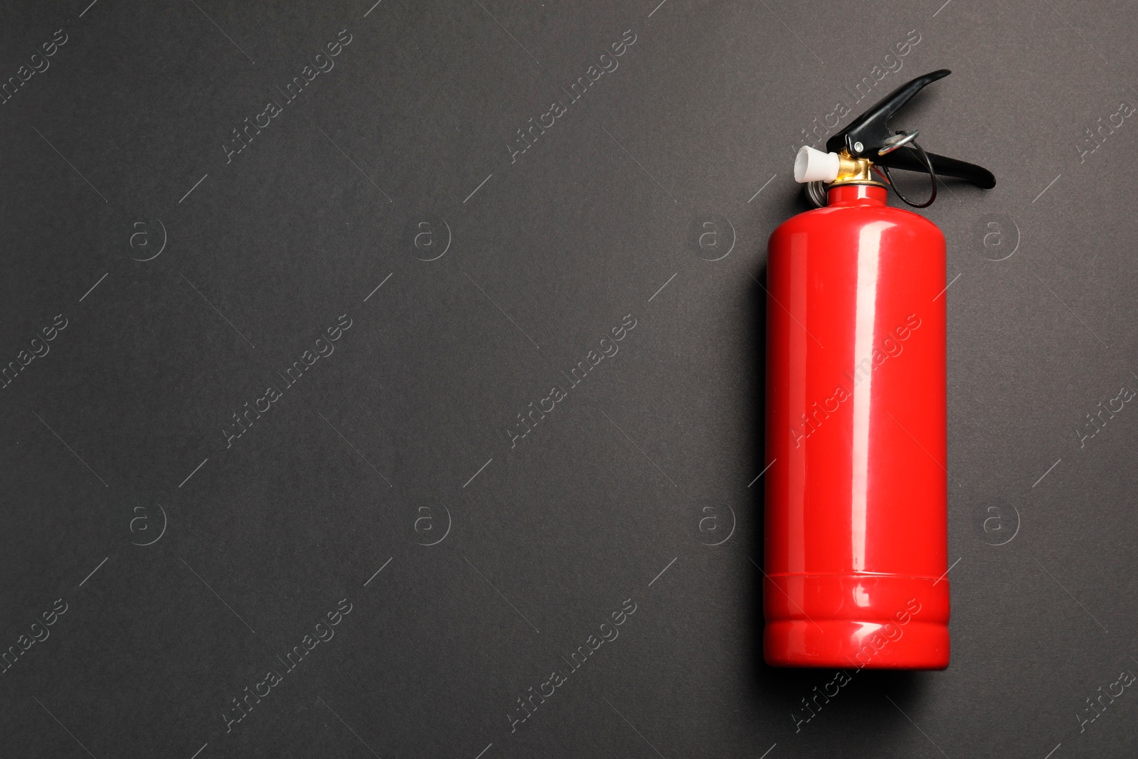 Photo of One red fire extinguisher on dark gray background, top view. Space for text