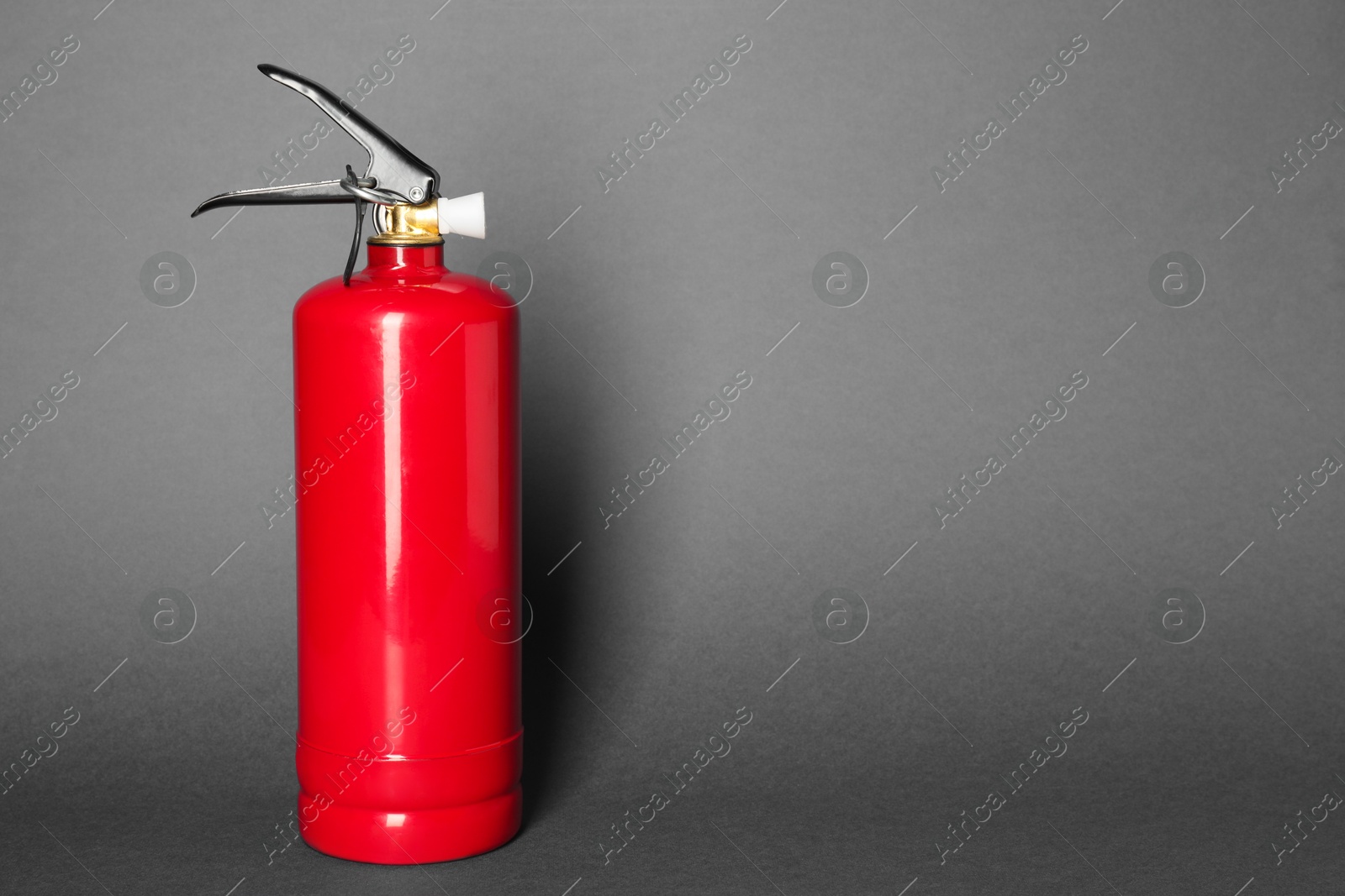 Photo of One red fire extinguisher on gray background, space for text