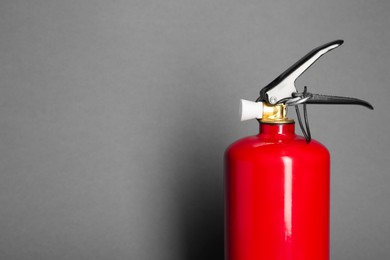 Photo of One red fire extinguisher on gray background, space for text