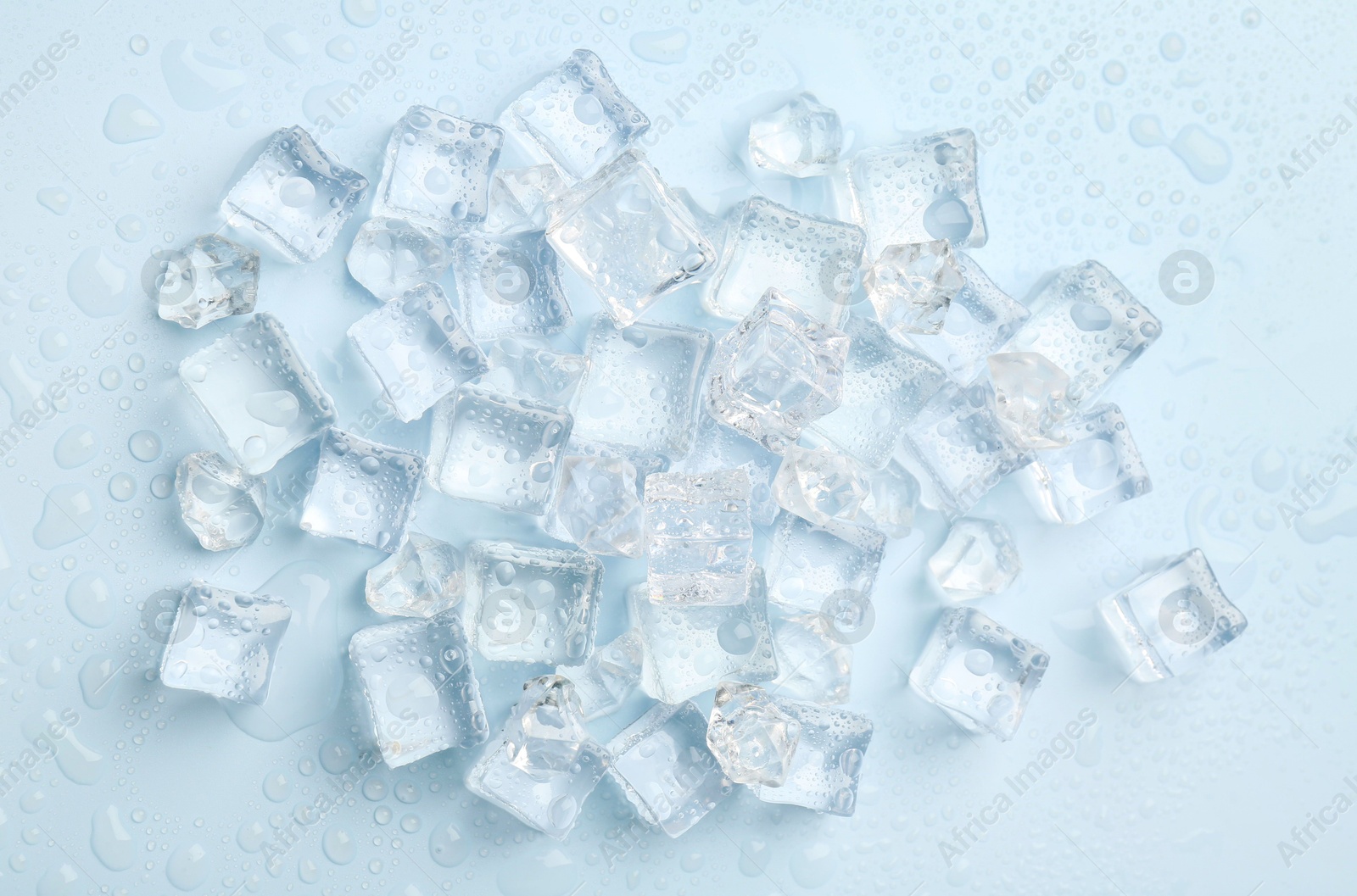 Photo of Crystal clear ice cubes on light blue background, flat lay