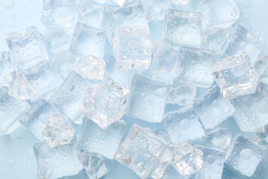 Crystal clear ice cubes on light blue background, flat lay