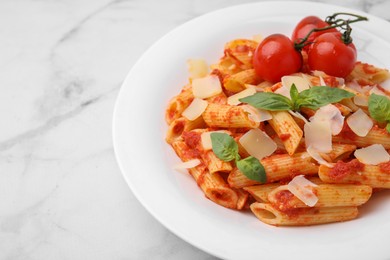 Tasty pasta with tomato sauce, cheese and basil on white marble table