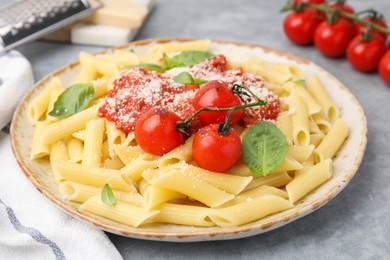 Tasty pasta with tomato sauce, cheese and basil on grey table