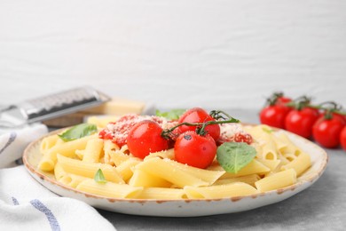 Photo of Tasty pasta with tomato sauce, cheese and basil on grey table