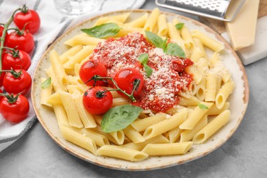 Photo of Tasty pasta with tomato sauce, cheese and basil on grey table