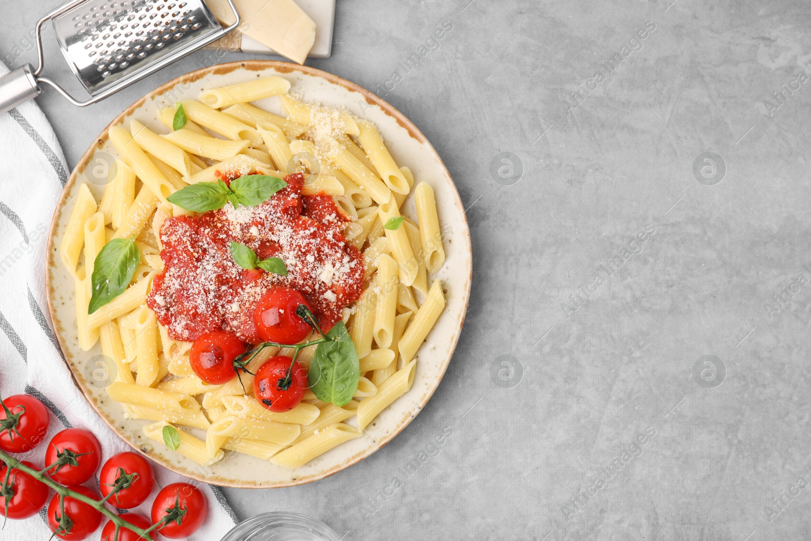 Photo of Tasty pasta with tomato sauce, cheese and basil served on grey table, top view. Space for text