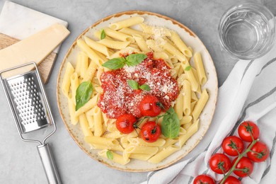 Photo of Tasty pasta with tomato sauce, cheese and basil served on grey table, flat lay