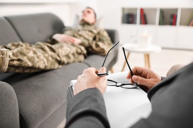 Photo of Professional psychotherapist working with military man in office, closeup