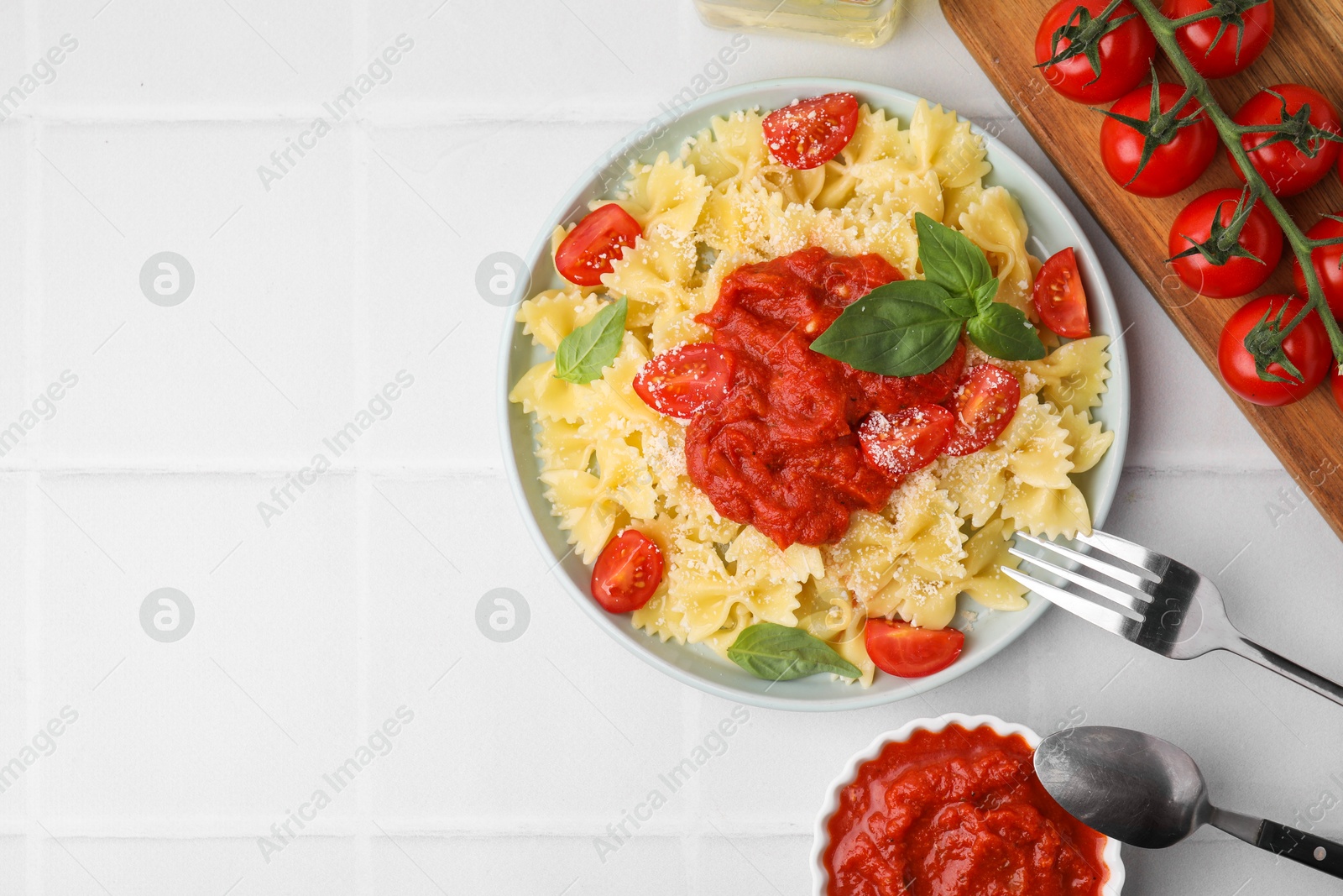 Photo of Tasty pasta with tomato sauce, cheese and basil served on white tiled table, flat lay. Space for text