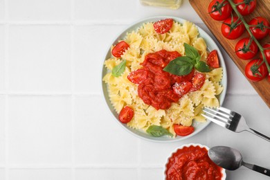 Tasty pasta with tomato sauce, cheese and basil served on white tiled table, flat lay. Space for text