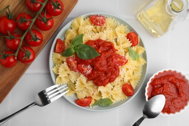 Photo of Tasty pasta with tomato sauce, cheese and basil served on white tiled table, flat lay