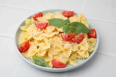 Photo of Tasty pasta with tomato, cheese and basil on white tiled table