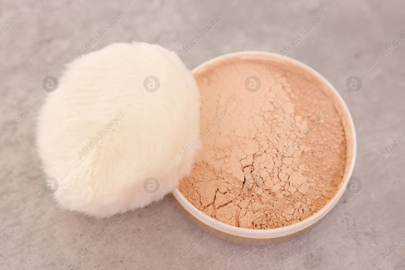 Photo of Face powder with puff applicator on grey textured table, above view