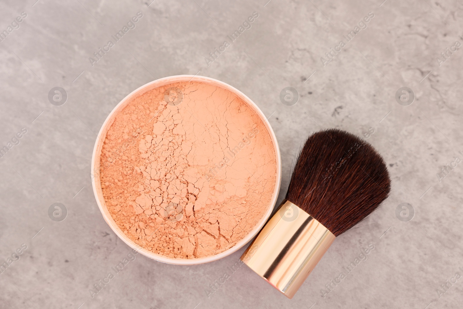 Photo of Face powder and brush on grey textured table, flat lay