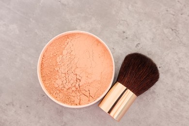 Photo of Face powder and brush on grey textured table, flat lay