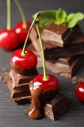 Fresh cherries with chocolate on grey wooden table, closeup