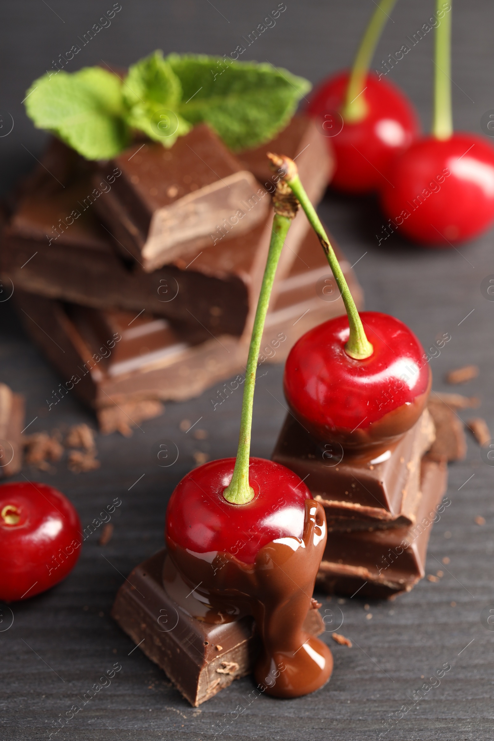 Photo of Fresh cherries with chocolate on grey wooden table, closeup