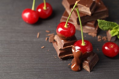 Fresh cherries with chocolate on grey wooden table, closeup. Space for text